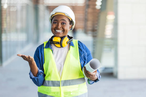 istock Architect with a blueprints at a construction site. Young Woman look in camera, building site place background. 1344212128