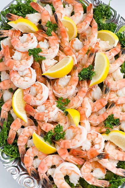 Pink Shrimp Cocktail Pink Shrimp Cocktail.  Fresh peeled and cooked shrimp fanned out on tray with yellow lemon wedges and green parsley sprigs. Beautiful soft window light. ProPhoto RGB. shrimp cocktail stock pictures, royalty-free photos & images