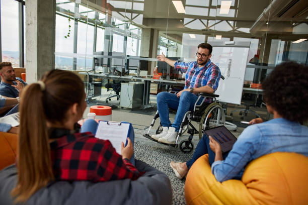istock Programmer in a wheelchair discussing business moments in a modern office 1344215360