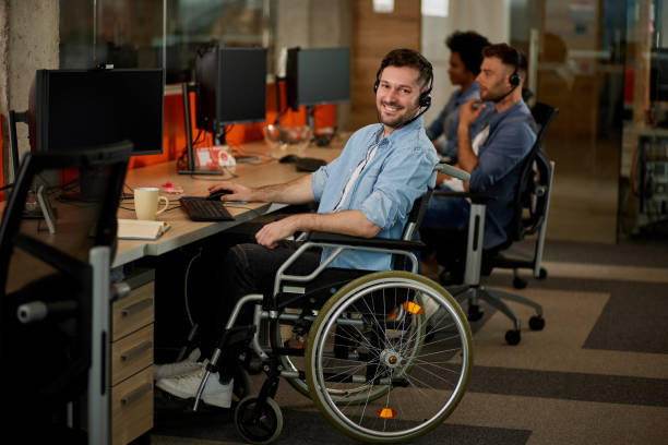 istock Handicapped computer programmer in wheelchair at his office desk 1344215385