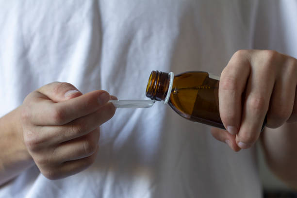 istock A young man pours medicine into a spoon to drink. 1344215423