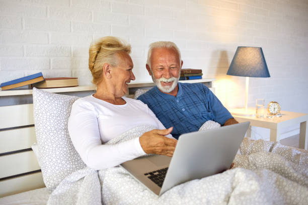 istock Retired senior couple using laptop while sitting in bed 1344215736