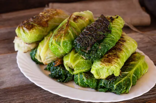 Traditional fresh fried german cabbage rolls called Krautroulade or Kohlroulade in Germany filled with delicious minced meat. Served on a plate on wooden table. Closeup and isolated view from above