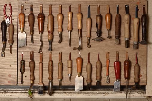 Juego de herramientas artesanales de cuero colgadas en la pared en taller. Lugar de trabajo para zapatero. Varias herramientas de zapatería hechas a mano. photo