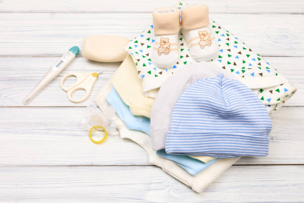 istock baby clothes and  attributes on a white wooden background. View from above 1344222871