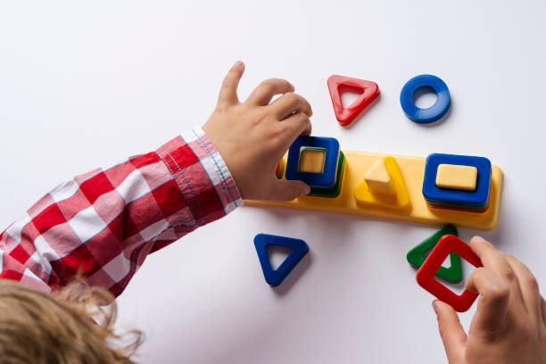 The child collects the sorter constructor. Puzzle sorter, an early development concept. Children's hands put the puzzle stock photo