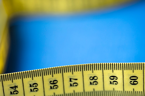 On the table is a long yellow ribbon with measurements for the seamstress. A yellow meter on a white background.