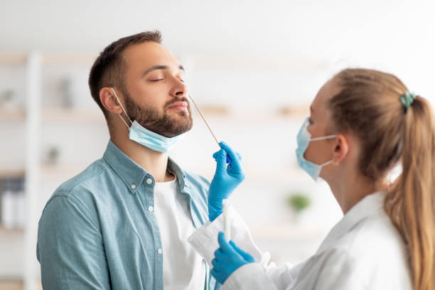 женщина-врач делает пцр-тест на коронавирус носа для парня-миллениала в клинике. концепция защиты от инфекционных заболеваний - медицинский анализ стоковые фото и изображения