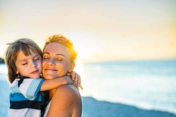 istock Loving single mother and son embracing on the beach at sunset. 1344231082