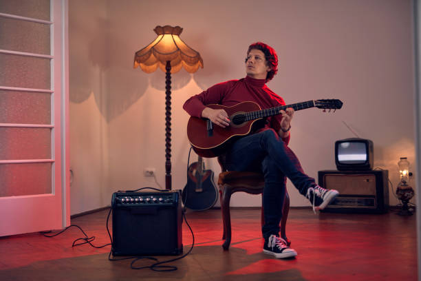 male musician playing acoustic guitar on the amplifier in retro vintage room. - fingerstyle imagens e fotografias de stock