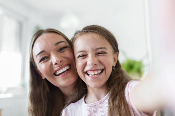 mała córeczka młoda matka patrzy z bliska na kamerę internetową. urocza dziewczyna korzysta ze smartfona baw się ze starszą siostrą robiąc selfie fotografię, vlogerzy nagrywają nowy vlog, cieszą się zabawną koncepcją aktywności - mothers audio zdjęcia i obrazy z banku zdjęć