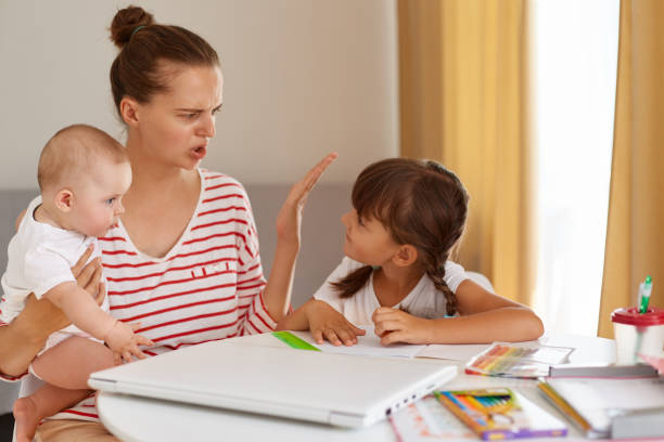 istock Mother becoming frustrated with daughter while doing homework sitting at table at home in learning difficulties homework, parenting and online education. 1344233689