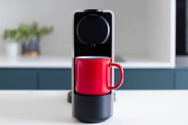 istock Capsule coffee machine and espresso in red cup. Fresh coffee is being made in modern cozy kitchen. Breakfast time 1344236464