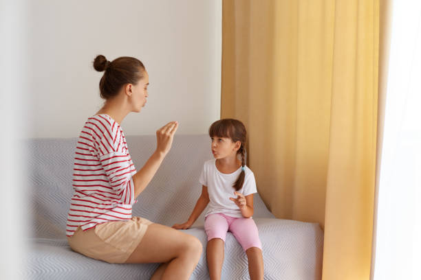 istock Back view of speech pathologist teaching little kid daughter right sounds pronunciation, physiotherapist working on speech defects or difficulties with small child girl indoors. 1344237600