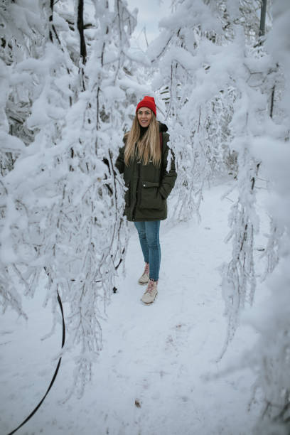istock Young woman walking between snowy woods 1344238829