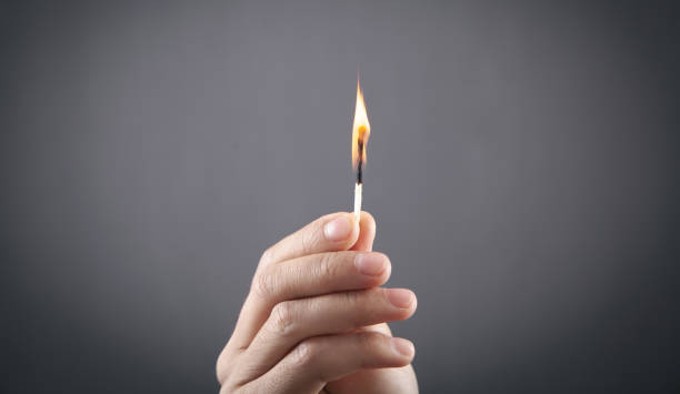 istock Burning match in male hand in grey background. 1344239241