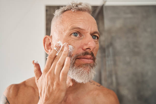 istock Mature man applying shaving foam on his face while standing in bathroom 1344239253