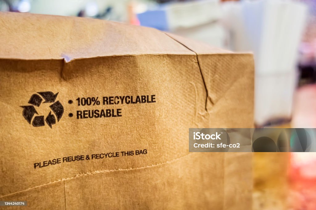 Brown paper bag that is 100% recyclable and reusable on a counter Brown paper bag that is 100% recyclable and reusable on a counter. A printed plea for user to recycle and reuse this bag as a form of packaging. Sustainable Lifestyle Stock Photo