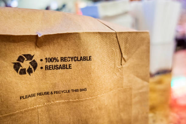 Brown paper bag that is 100% recyclable and reusable on a counter Brown paper bag that is 100% recyclable and reusable on a counter. A printed plea for user to recycle and reuse this bag as a form of packaging. ecological reserve photos stock pictures, royalty-free photos & images