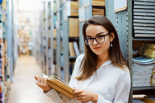 istock Beautiful girl with old book in library 1344242026