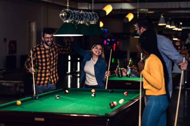 istock Four smiling friends in bar playing billiard together. 1344243246