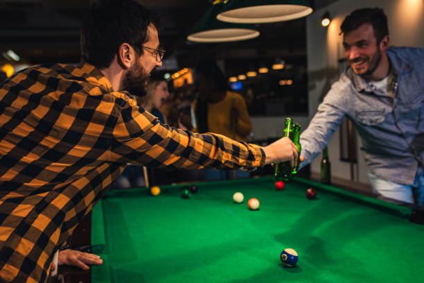 istock Four smiling friends in bar playing billiard together. 1344243457