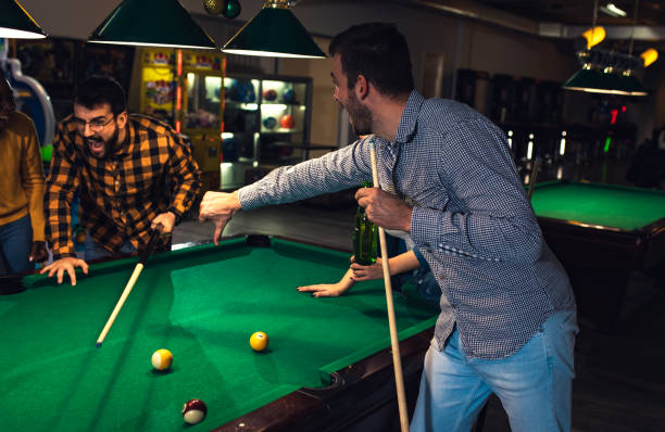 istock Four smiling friends in bar playing billiard together. 1344243700