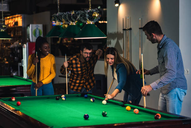 istock Four smiling friends in bar playing billiard together. 1344243754