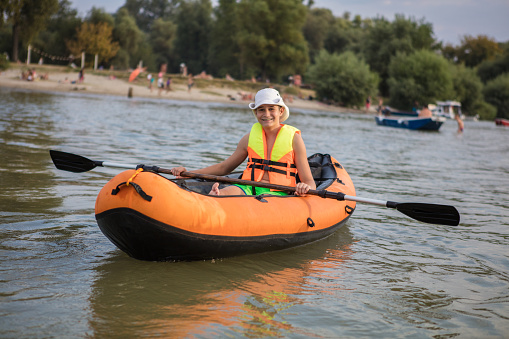 Gen alpha teenager smiling and kayaking on a lake