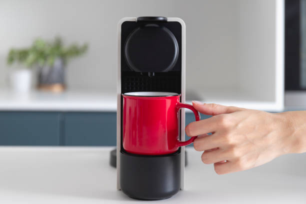 istock Capsule coffee machine and espresso in red cup. Fresh coffee is being made in modern cozy kitchen. Breakfast time 1344244427