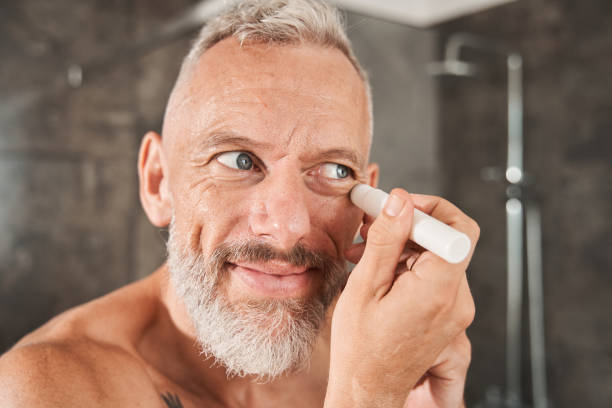 istock Mature man apply under eye concealer on face 1344244544