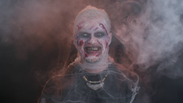 istock Sinister devil man with scary Halloween dead zombie makeup in costume making faces, trying to scare 1344246014