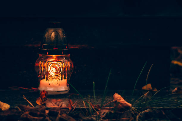 burning candle in lantern during All Saints Day on grave on cemetery
