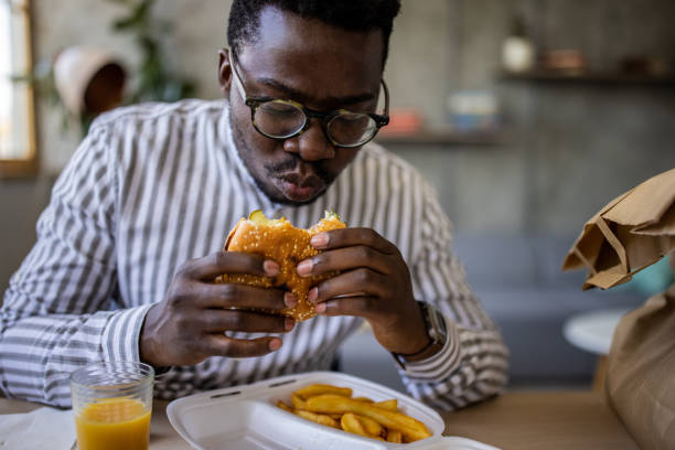 istock Young businessman eating burgers while telecommuting from home 1344246466