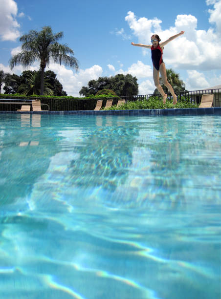 istock Elementary age girl jumping in to swimming pool 1344246656