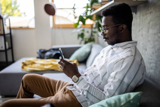 istock Young man surfing the net while sitting on sofa at home 1344247441