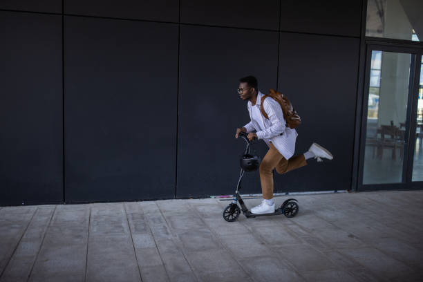 istock Young businessman in rush to get to work on time with push scooter 1344247514