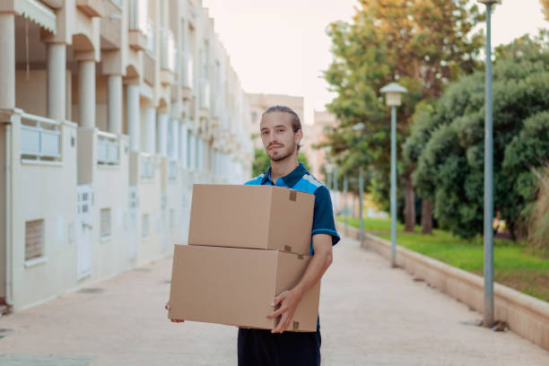 istock Delivery boy holding two boxes in the neighborhood 1344247570