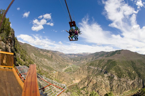 Amusement Park Ride with Man and Woman on Swing Over Canyon