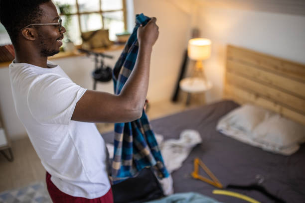 istock Young man packing clothing for vacation in suitcase before travel 1344249251