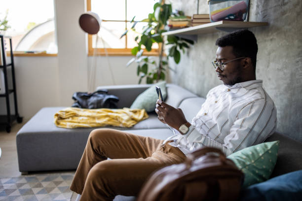 istock Young man surfing the net while sitting on sofa at home 1344249253
