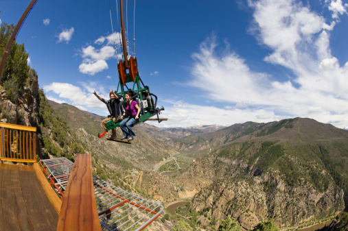 Amusement Park Ride with Man and Woman on Swing Over Canyon