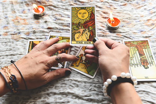 Show fortune tellers of hands holding tarot cards and tarot reader with candle light on the table, Performing readings magical performances, Things mystical astrologists forecasting concept