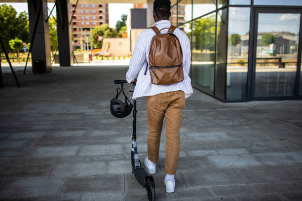istock Young businessman going home after work with push scooter 1344249519