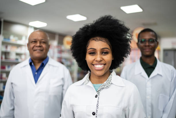 ritratto di una giovane farmacista con i suoi colleghi in farmacia - healthcare and medicine smiling group of people lab coat foto e immagini stock