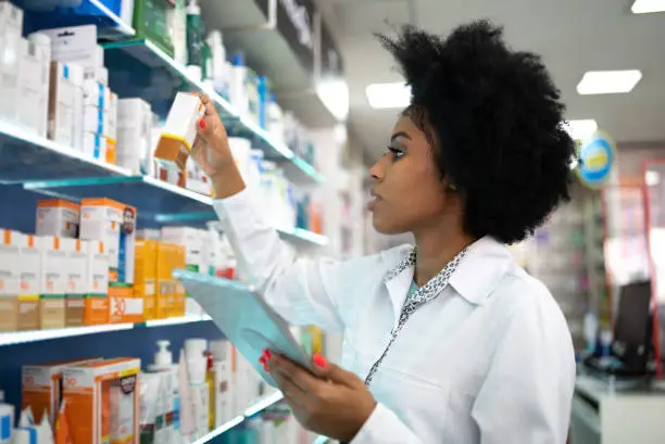 Photo of Young pharmacist checking the shelves with a digital tablet at the pharmacy