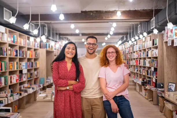 Portrait of a female librarian/bookseller of Asian ethnicity, and her male and female employee