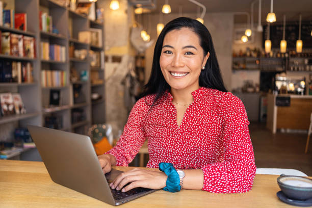 Modern young woman of Asian ethnicity, e-learning via laptop, at the modern and cozy cafeteria Portrait of a charming and modern young woman of Asian ethnicity, e-learning via laptop, at the modern and cozy cafeteria one young woman only stock pictures, royalty-free photos & images