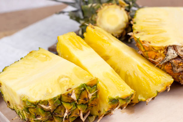 istock Fresh juicy yellow pineapple fruit slices on light wooden board background 1344254464