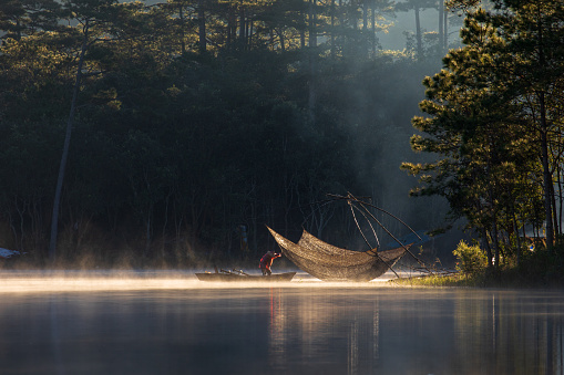 Fisherman in Tuyen Lam lake in a foggy morning, Da Lat city, Lam Dong province, central high lands Vietnam